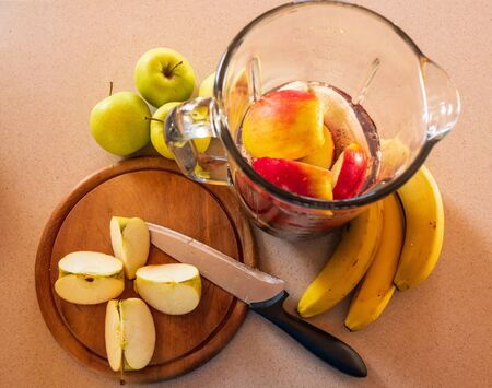 flat-lay of a blender on a kitchen digital scale with blueberries and nuts, and around bananas and apples and a knifeの写真素材