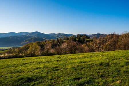 green field in the mountains with a valley below and the sun on the horizon, czechの写真素材
