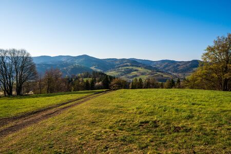 green field in the mountains with a valley below and the sun on the horizon, czechの写真素材
