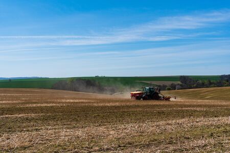 Farmer in tractor sowing wheat field at spring , czech jeseniky 04.16.2020の写真素材