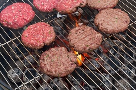 Close-up view of meatball grilling on barbecue. Grilled burger on barbecue grill with smoke and black background. .の写真素材