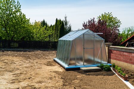 greenhouse in the garden with brown soil aroundの写真素材
