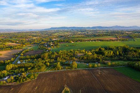 aerial view of forest and green field with several housesの写真素材