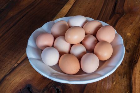 fresh brown and white chicken eggs on a plate with woodenの写真素材