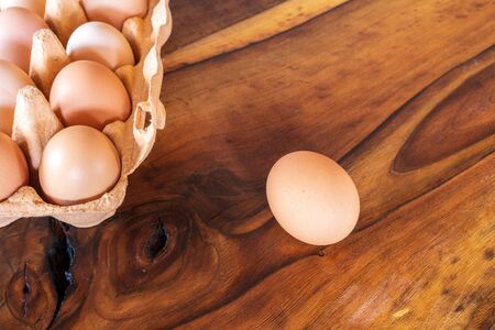 Detail close-up of chicken eggs in egg box on the old brown wooden background.の写真素材