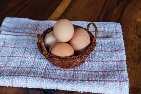 egg in a bowl on a tea towel on a wooden kitchen counterの写真素材