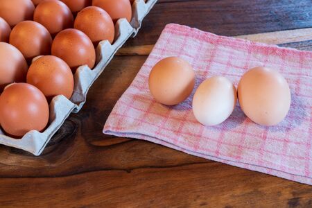 Detail close-up of chicken eggs in egg box on the old brown wooden background.の写真素材