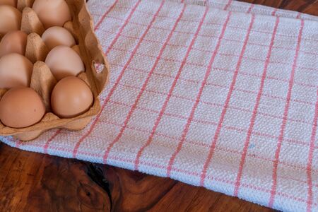 Detail close-up of chicken eggs in egg box on the old brown wooden background.の写真素材