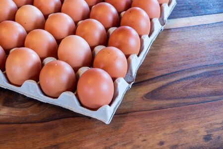 Chicken eggs in egg carton box on wooden backgroundの写真素材