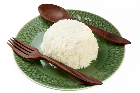 Rice on green plate with wood spoon and fork isolated on white backgroundの写真素材