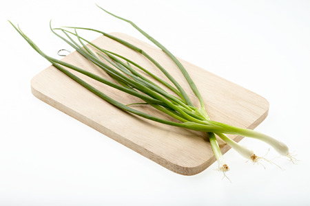 Scallion on chopping block isolated on white background.の写真素材