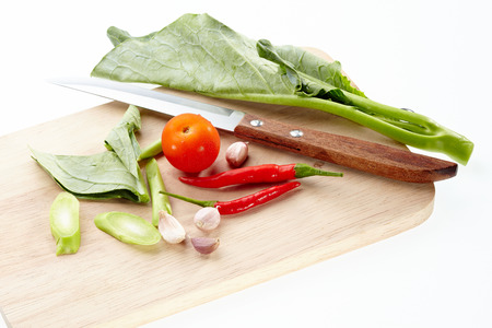 Collard, tomato, red chilli, garlic and knife on chopping block isolated on white background.の写真素材