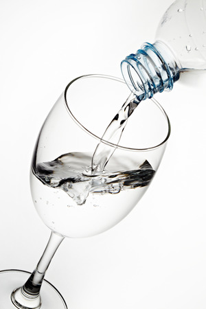 Pouring water from bottle to the glass isolated on white backgroundの写真素材
