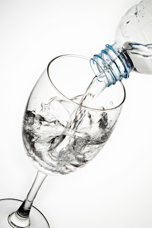 Pouring water from bottle to the glass isolated on white backgroundの写真素材