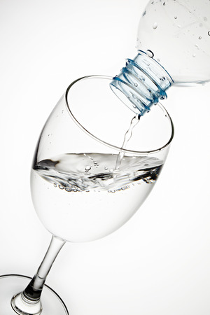 Pouring water from bottle to the glass isolated on white backgroundの写真素材