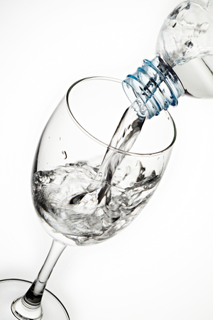 Pouring water from bottle to the glass isolated on white backgroundの写真素材