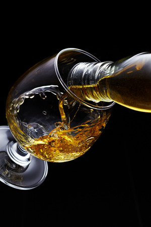 Whisky pouring in glass isolated on black backgroundの写真素材