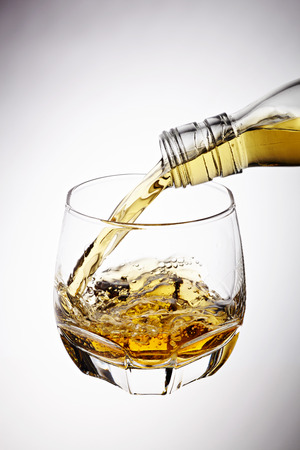 Whisky pouring in glass isolated on white backgroundの写真素材