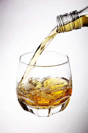 Whisky pouring in glass isolated on white backgroundの写真素材