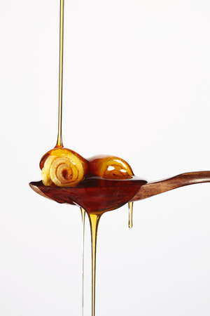 Honey pouring on pancake in wood spoon isolated on white backgroundの写真素材