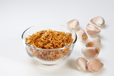 Fried garlic in glass bowl and garlic isolated on white backgroundの写真素材