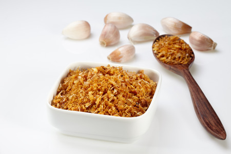 Fried garlic in white bowl and wood spoon and garlic isolated on white backgroundの写真素材