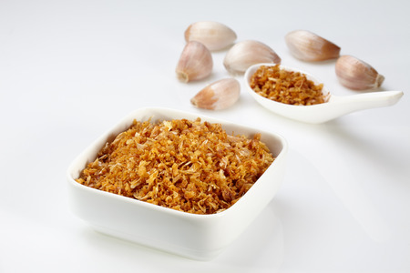 Fried garlic in white bowl and spoon and garlic isolated on white backgroundの写真素材