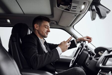 Smiling young man reading message in car