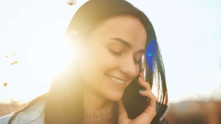 Close up portrait of an adorable young lady taking pleasure from a cheerful phone conversation and...