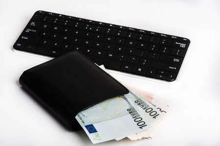 The European currency euro in a black wallet and keyboard.の写真素材