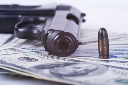 Gun with bullet on US dollar banknotes, crime and corruption.の写真素材
