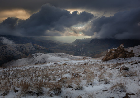 the landscape. first snow. village in a mountain valley with heavy snow clouds.の写真素材