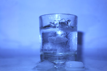 Glass of water with ice cubes on a white background, close-up