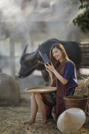 Asian woman in traditional dress listen radio outdoor,countryside Thailand.の写真素材