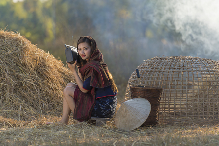 Asian beautiful girl wearing thai traditional dress,lying and listen radio on the straw.の写真素材