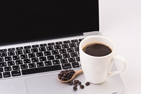Coffee cup and beans turn on computer laptop on white backgroundの写真素材