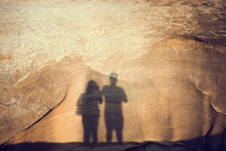 shadow of two people on the big stone or stone wall