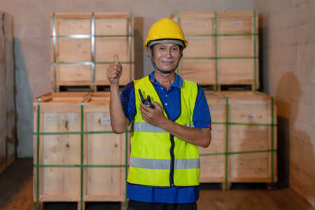 portrait of factory warehouse worker with communication radio in storage warehouseの写真素材