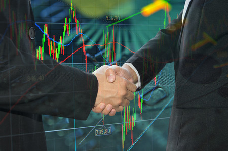 Business shaking hand on finacial graph background.の写真素材