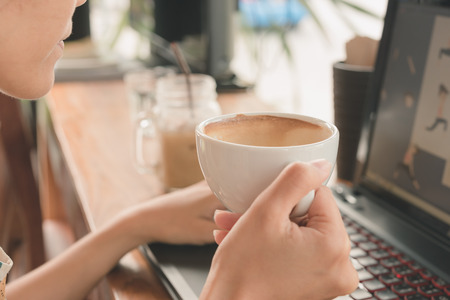 woman drinking coffee and using computer in coffee shop.の写真素材