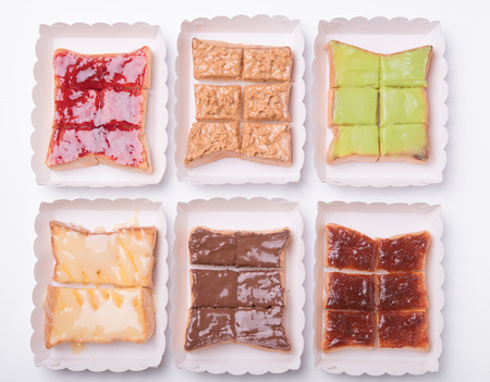 Sweetened condensed milk, strawberry jam, peanut butter on slice bread toast isolated on white...