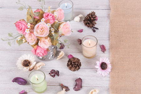 still life interior decoration pink rose flower in a vase with book and candle on rustic wooden table background.の写真素材