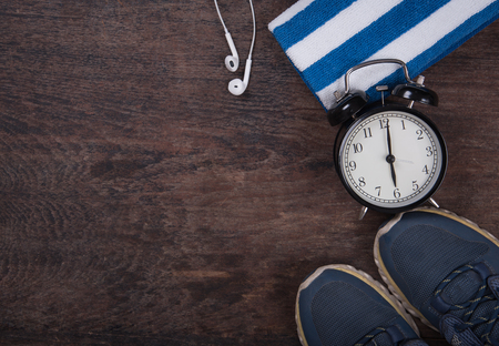 Fitness with clock, shoes,towel and headphones. Top View from above on wooden background.の写真素材