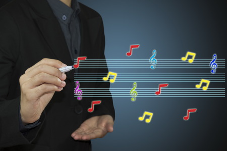 businessman hand holding pen writing music notes
