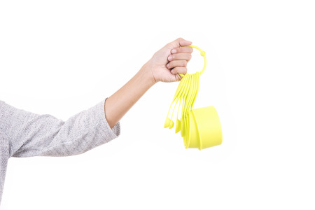 Woman hand holding green measuring cups isolated on white background.の写真素材