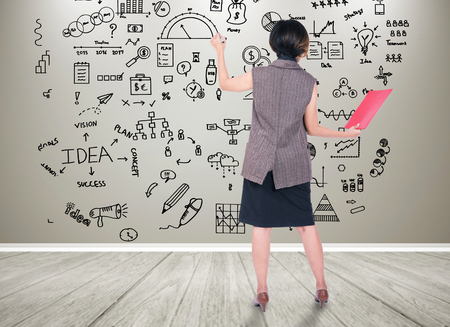 Businesswomen writeing financial analysis graph with key performance indicators on wall.の写真素材