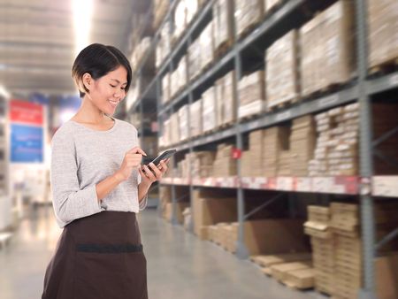 warehouse manager hand holding calculator in a large warehouse.