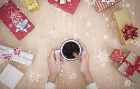 women hand holding hot chocolate on wood table with gift box and snowflake.の写真素材