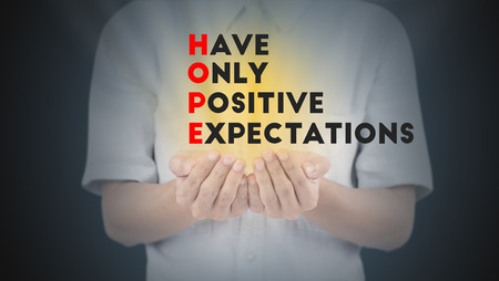 Hand with wording hope, have, only, positive, expectation and gold light.の写真素材