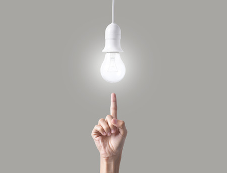 Business hand point light bulb on gray background. concept of new ideas with innovation and creativity.の写真素材